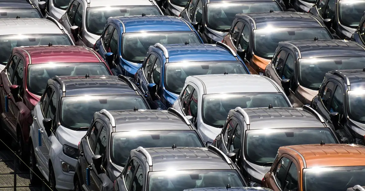 Rows of new cars lined up closely at a vehicle storage lot