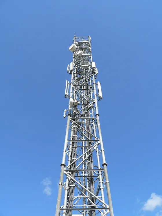 Steel lattice tower with antennas seen from below against a blue sky