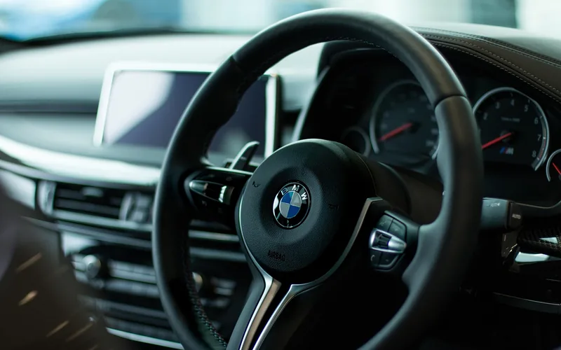 Modern car steering wheel with built-in audio control buttons visible on the spoke Modern car steering wheel with built-in audio control buttons visible on the spoke