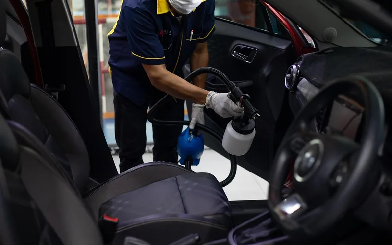 Hand washing a car exterior with soap and sponge in preparation for a rideshare inspection