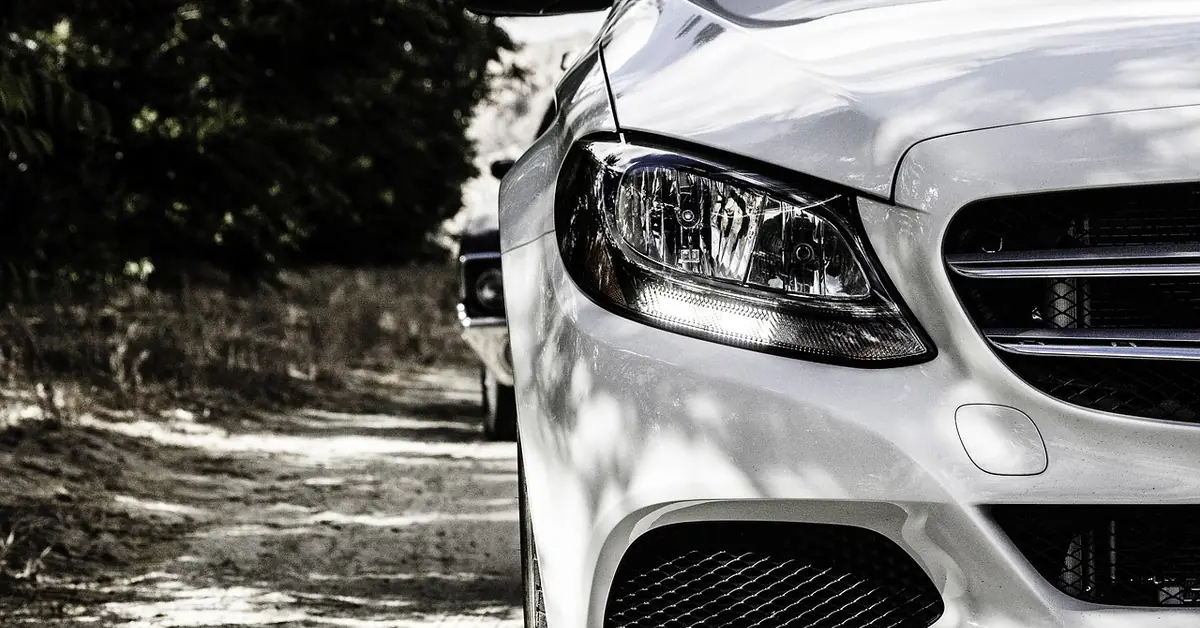 White car front end with a headlight and a lower light strip in daylight