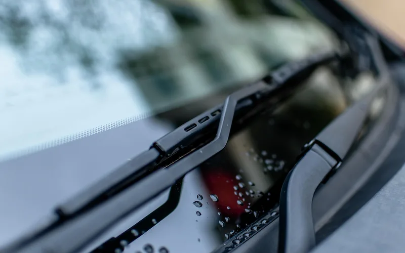 Windshield wiper blade on wet glass Close-up of a car windshield wiper blade resting on wet glass