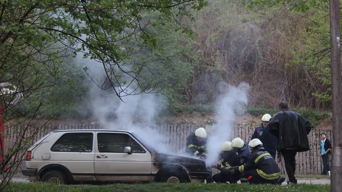 Flames and smoke rising from a car engine bay during a vehicle fire