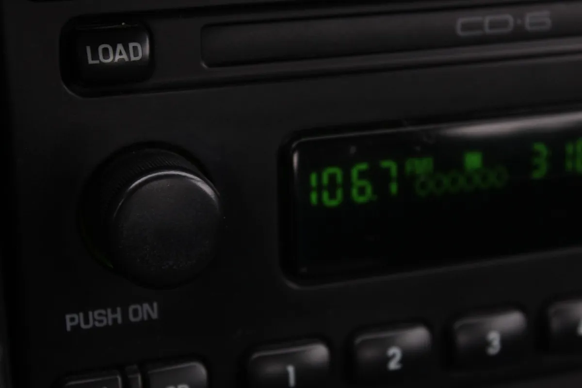 Car stereo head unit with a CD slot, load button and green radio display