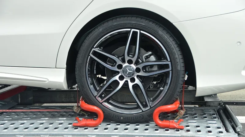 Car wheel secured with straps on a transport carrier
