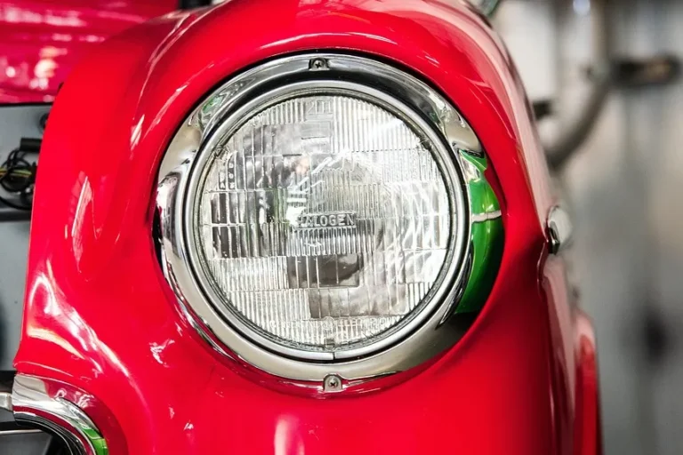 Glossy red car fender and round headlight on a classic car