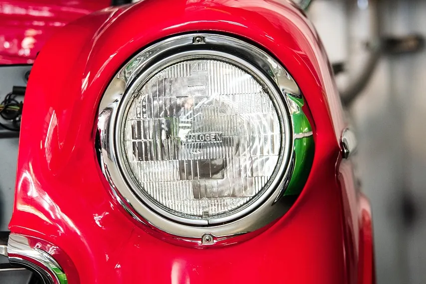 Glossy red car fender and round headlight on a classic car