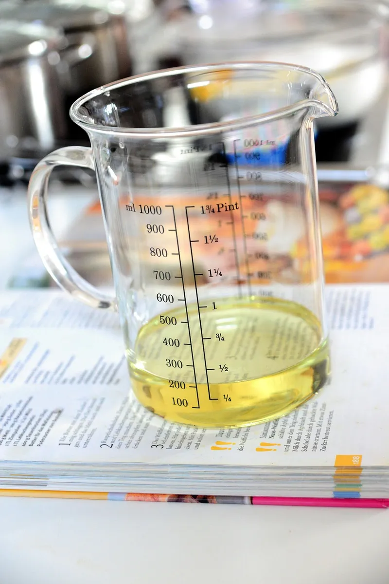 Glass measuring jug with milliliter and pint graduation marks holding a yellow liquid