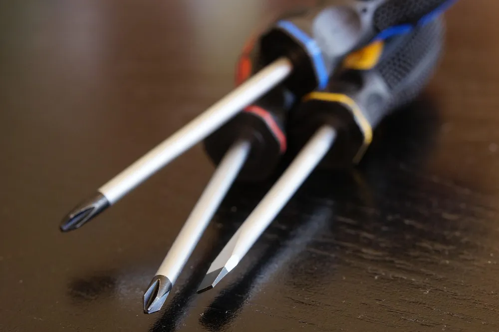 One flat-blade and two Phillips screwdrivers lying on a dark surface