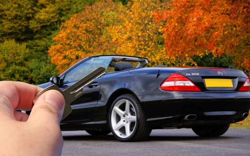 hand holding a spare car key next to a car door hand holding a spare car key next to a car door