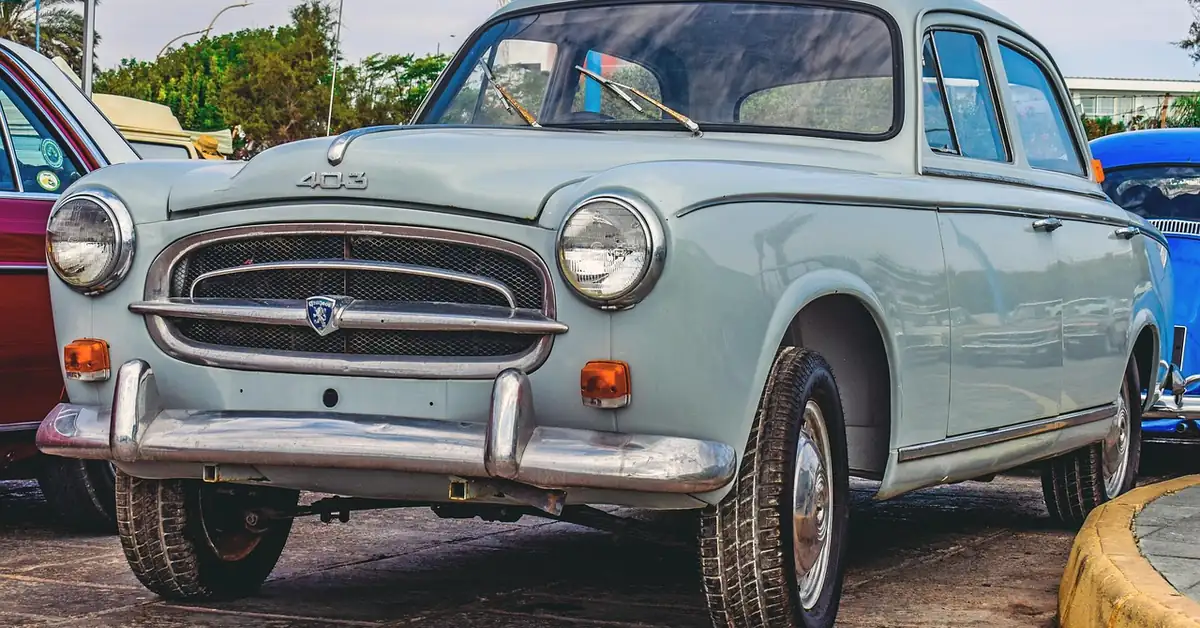 Grey Peugeot 403 saloon parked at a classic car meet, front three-quarter view