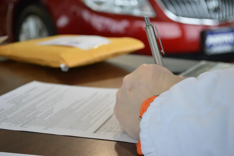Signing car purchase paperwork Signing car purchase paperwork at a dealership desk