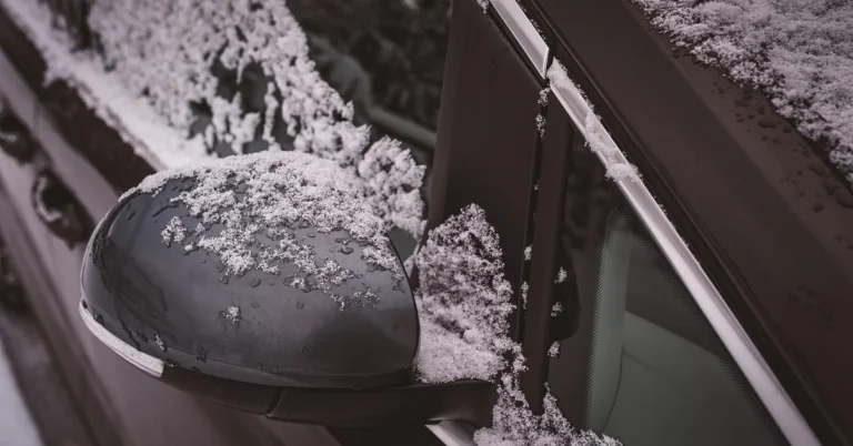 Snow on a car side mirror and window frame