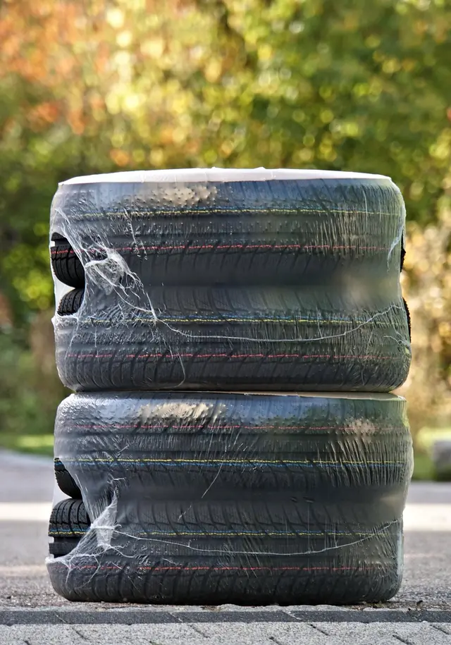 Two car tires stacked and wrapped in plastic film