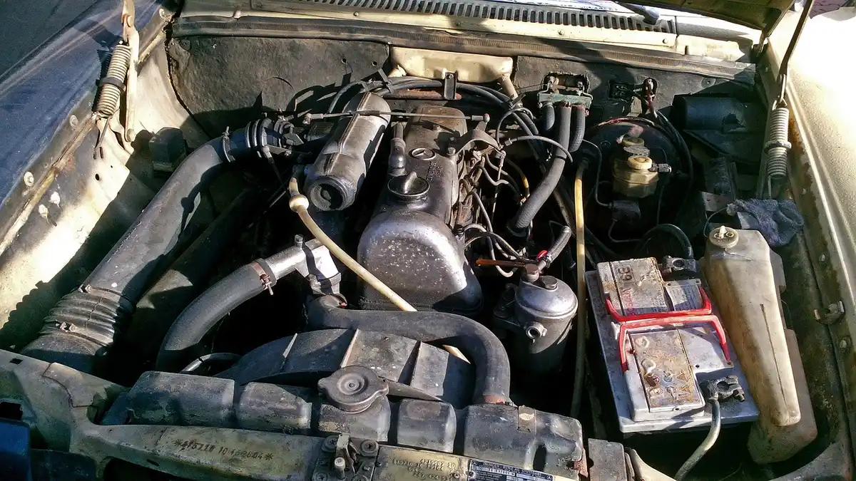Old, corroded car battery in an engine bay showing signs of age