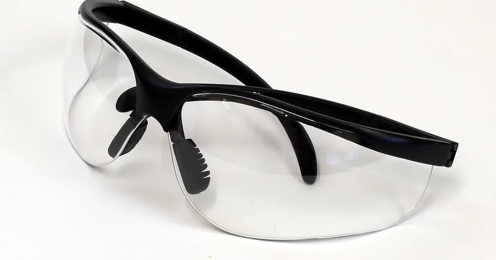 Clear safety glasses with a black frame on a white surface