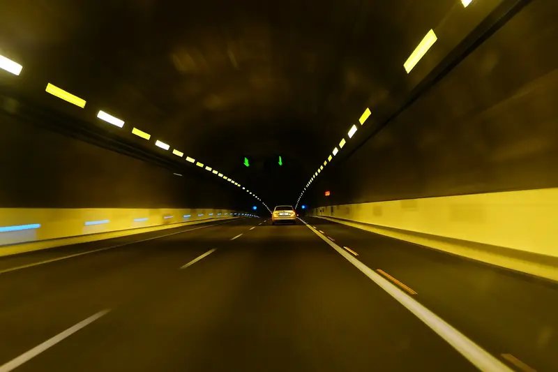 Car driving ahead inside a lit road tunnel