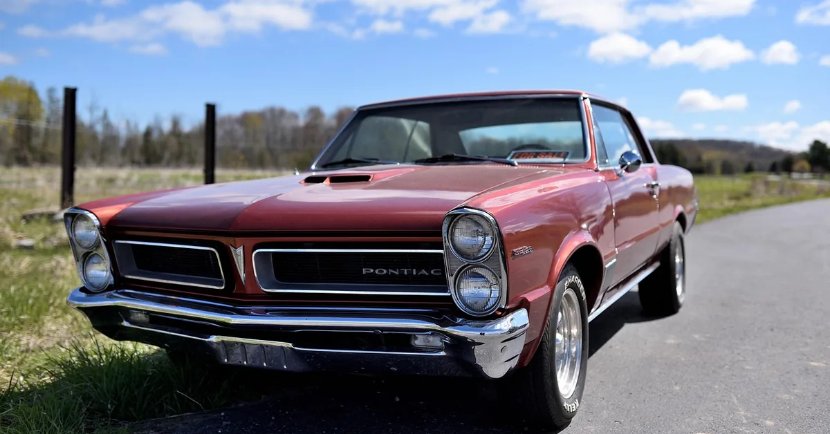Classic red 1965 Pontiac muscle car parked on a rural Michigan road