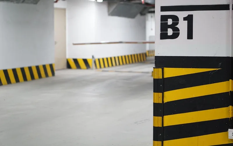 Empty bay in an underground parking garage with yellow and black marked pillars