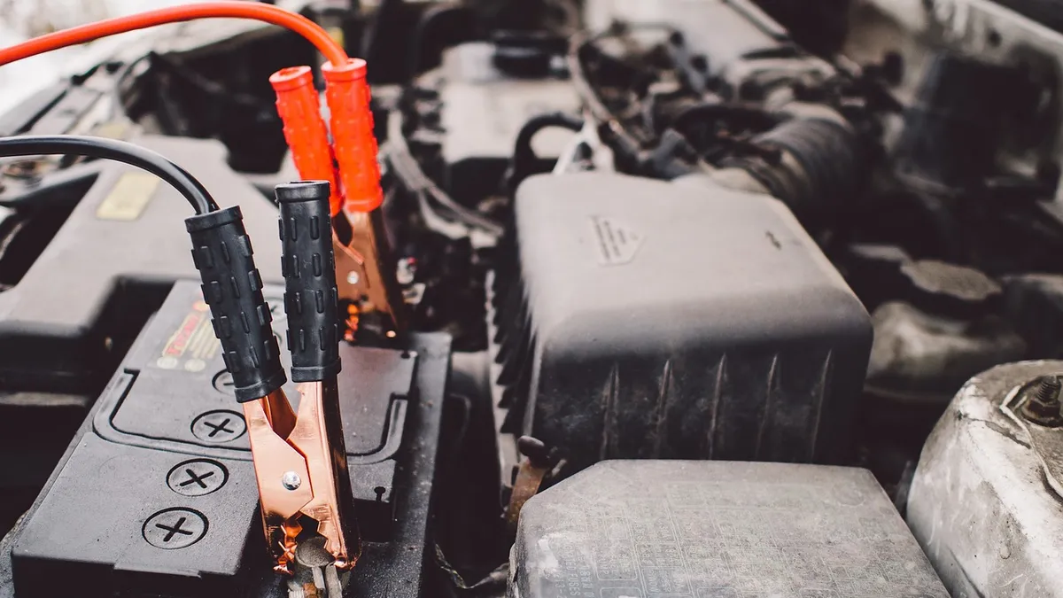 Jumper cables connected to a car battery terminal during a jump start