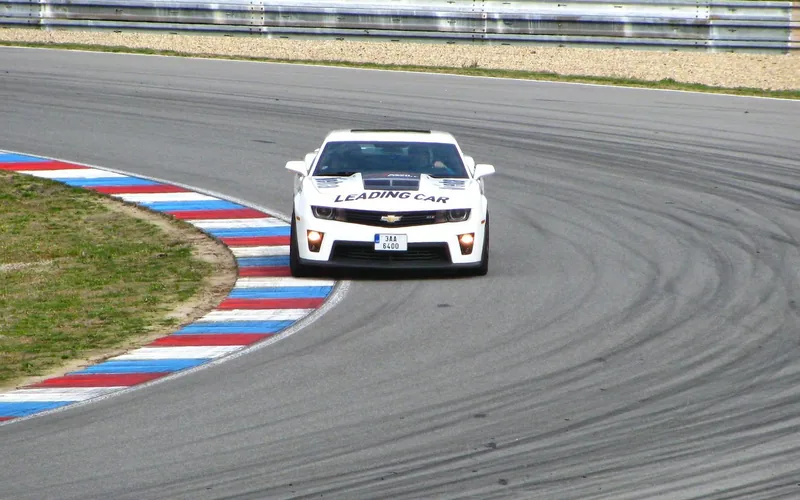 Pace car leading a line of race cars on a circuit during a caution period Pace car leading a line of race cars on a circuit during a caution period