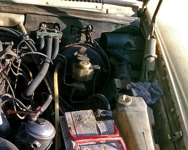 Older car engine bay with the battery sitting in its tray at lower right