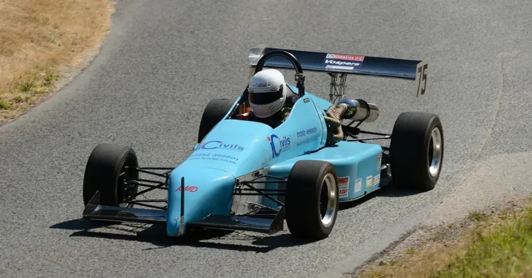 Light blue open-wheel single-seater race car cornering on a paved track