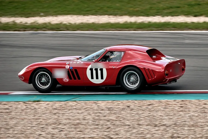 Red vintage Ferrari grand touring race car at speed on a circuit