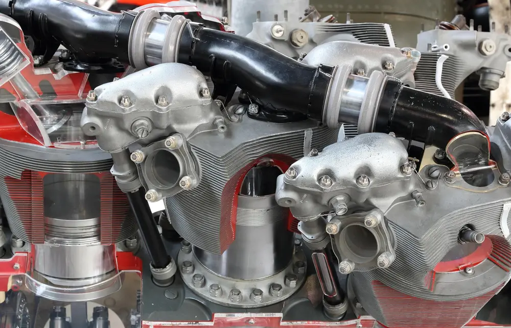 Cutaway of a multi-cylinder piston engine with cooling fins and a piston visible inside a cylinder