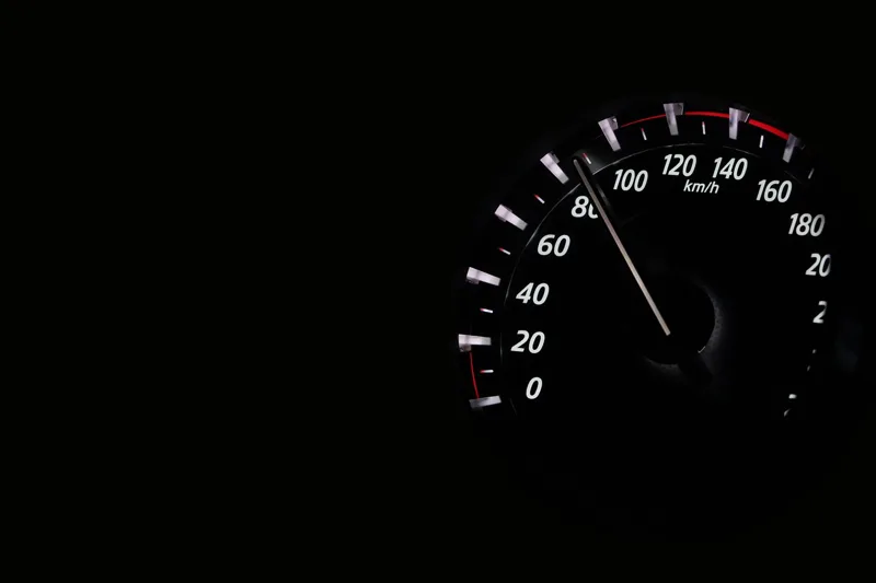Illuminated analog speedometer dial in a dark car instrument cluster