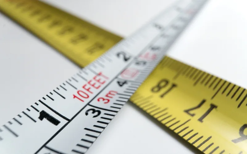 Close-up of a tape measure with a feet scale and a metre scale printed side by side