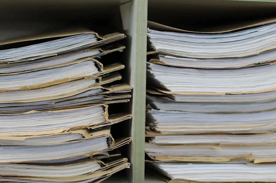 Stacks of paper files and folders in a storage shelf