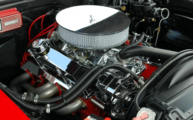 Open engine bay of a car with a chrome air cleaner and red hoses