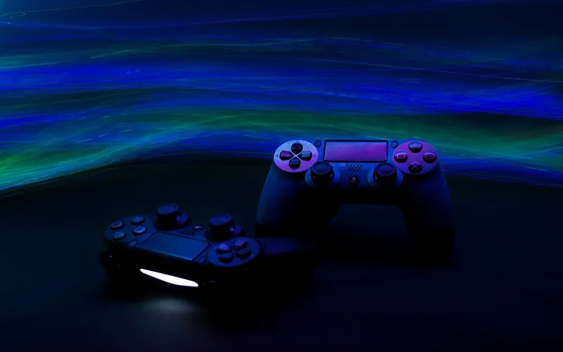 Two game controllers lit by colored ambient light in a home gaming setup