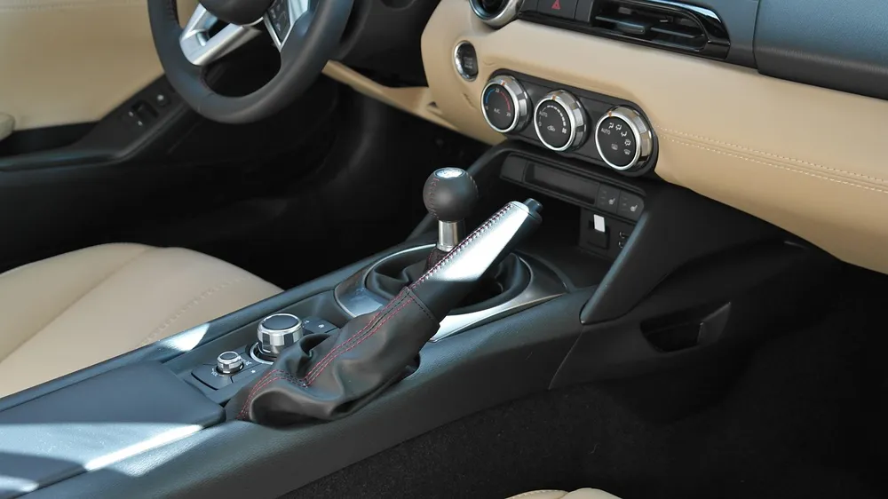 A car center console with a shift lever, rotary controls and climate dials