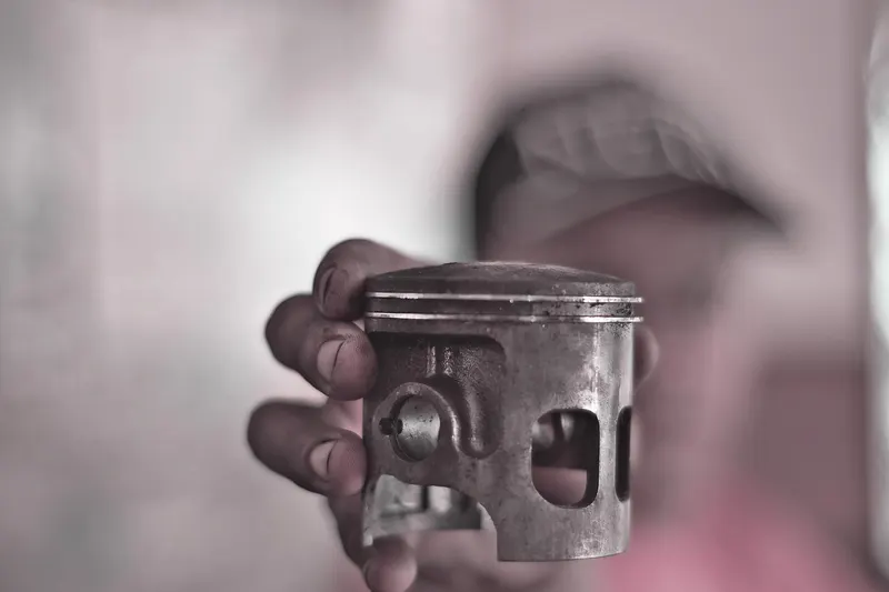A mechanic holding up a used engine piston