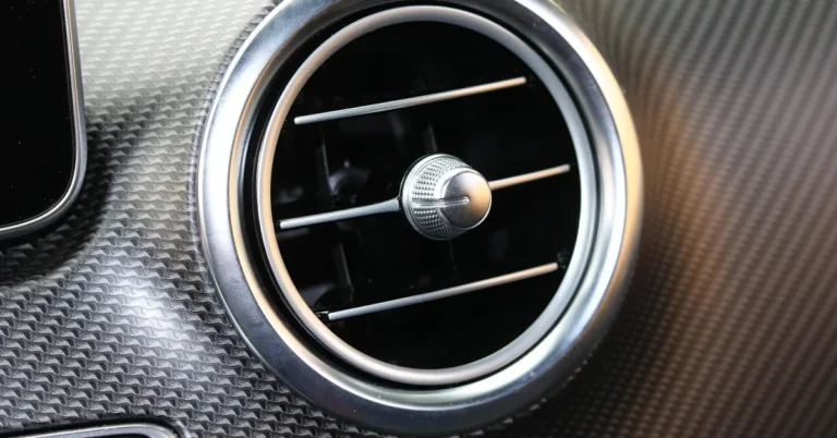 Round car dashboard air vent with an adjustable center vane on textured trim