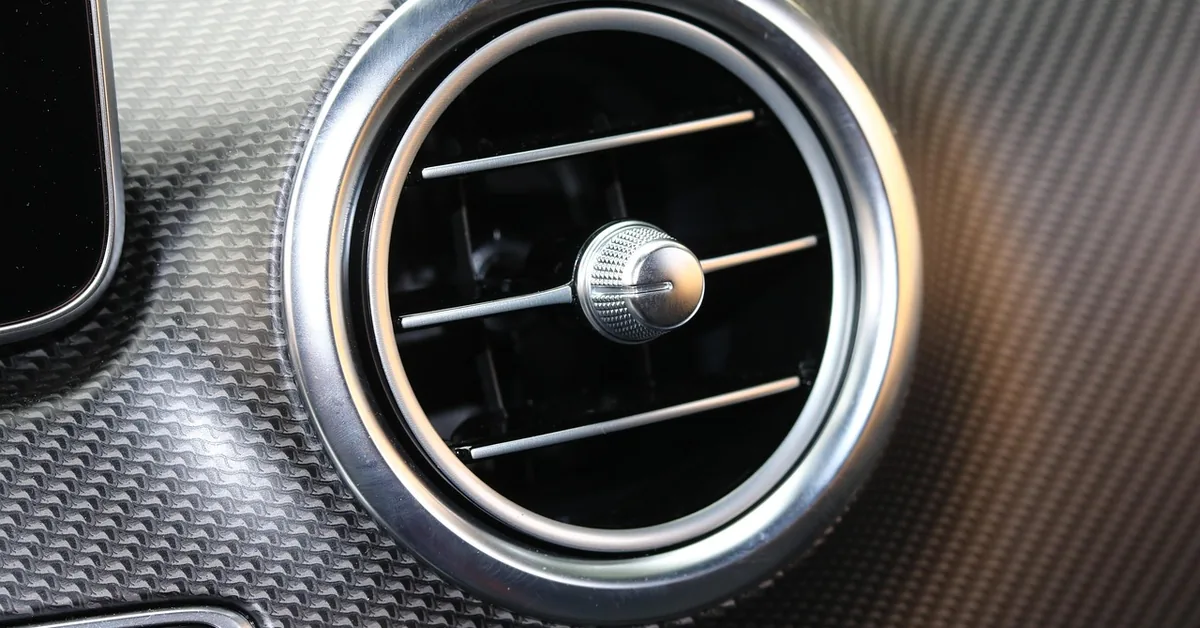 Round car dashboard air vent with an adjustable center vane on textured trim