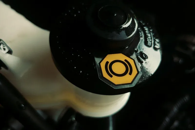 Brake fluid reservoir cap marked with a yellow brake warning symbol