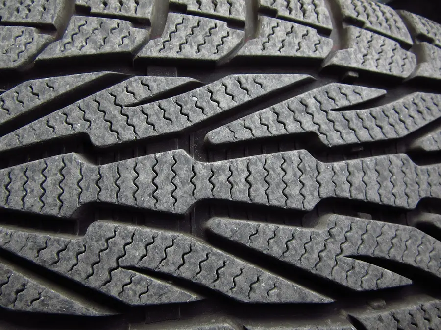 Close-up of a car tire tread with zigzag cuts in the tread blocks