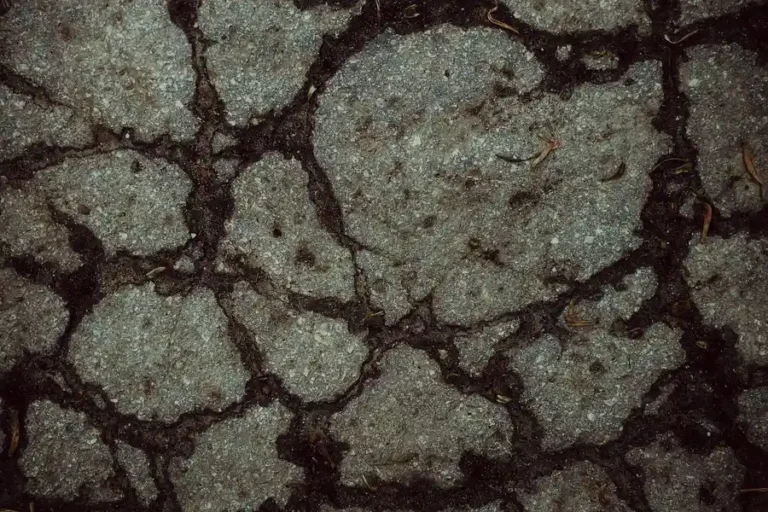 Cracked and broken asphalt road surface seen from above