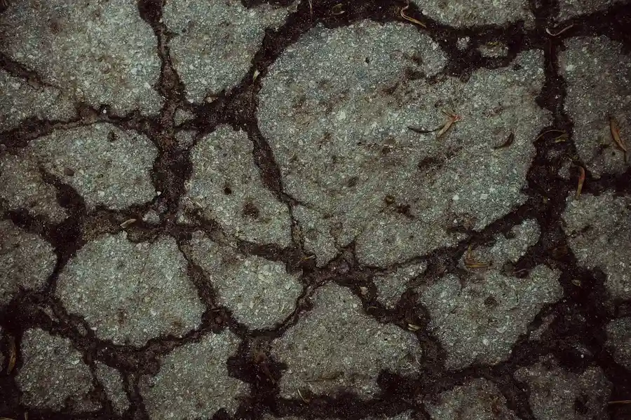 Cracked and broken asphalt road surface seen from above