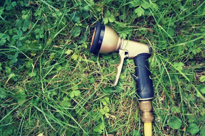 Hose-end spray nozzle with a pistol grip lying in grass
