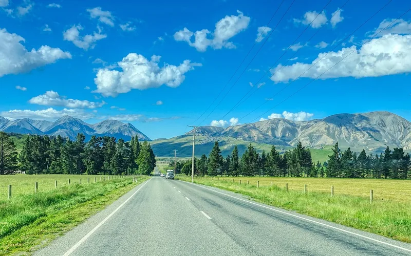 Open two lane road with a wide clear sky and mountains ahead