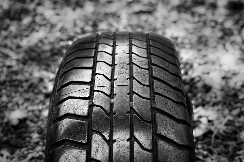 Close-up of a car tire tread with grooves and wear bars on the ground