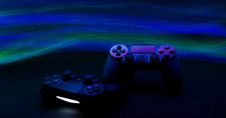 Game console controllers lit by neon light on a dark surface