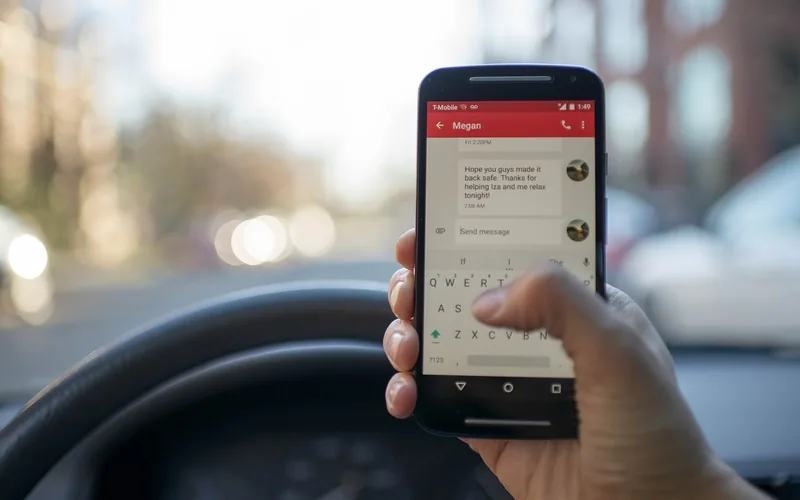 Driver holding a smartphone in front of a car dashboard while pairing Bluetooth