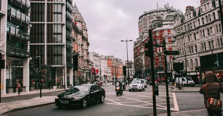 Cars driving through a central London street with historic buildings