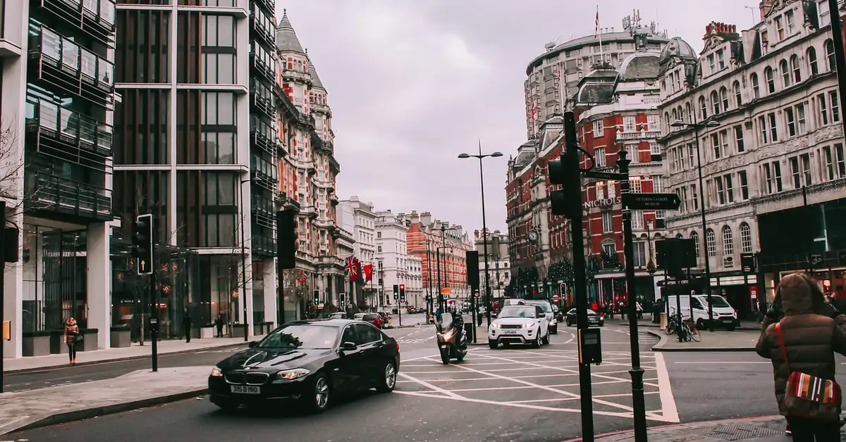 Cars driving through a central London street with historic buildings