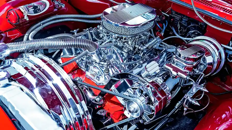 Chrome-plated engine compartment under the open hood of a red car